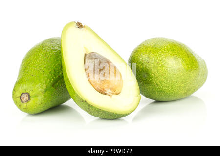 Two green smooth avocado and one sliced half with a brown seed isolated on white background bacon variety Stock Photo