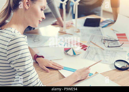 Taking measurements. Competent worker bowing head while looking downwards and using ruler with pencil Stock Photo