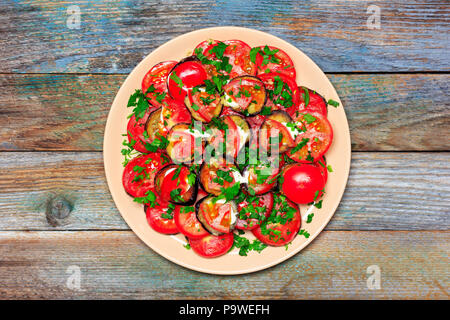 fried eggplant with tomato, garlic and mayonnaise on a wooden retro background, top view of a closeup Stock Photo