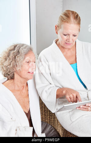 Two senior women using tablet computer at the spa hotel on vacation Stock Photo