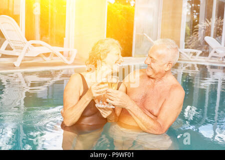 Senior couple drinking champagne at the hotel pool during a spa vacation Stock Photo