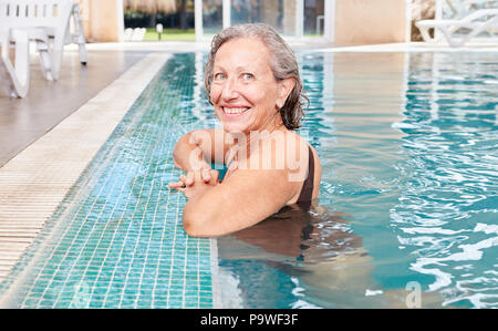Vital senior woman at the poolside in a swimming pool or spa hotel Stock Photo