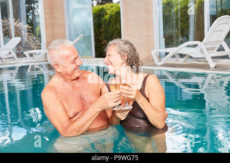 Couple in love seniors drinking champagne together in the pool at the Wellness Hotel Stock Photo