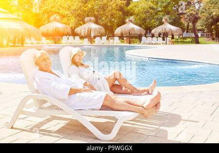 Happy senior couple relaxing on spa vacation on deckchair Stock Photo