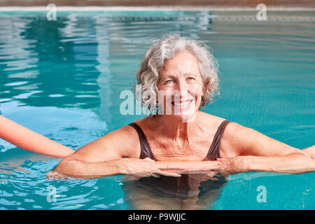 Smiling senior woman is doing aqua fitness with a swimming aid in the swimming pool Stock Photo
