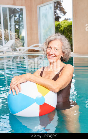 Smiling senior woman with a colorful ball makes aqua fitness in the pool Stock Photo