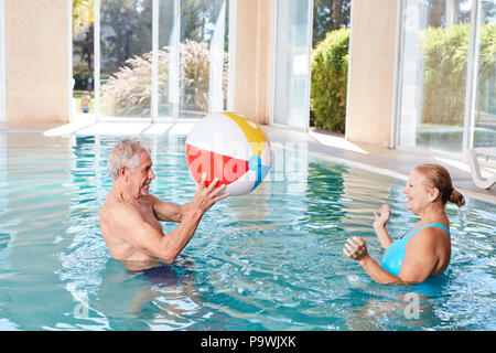 Senior couple plays water polo in spa swimming pool during wellness vacation Stock Photo