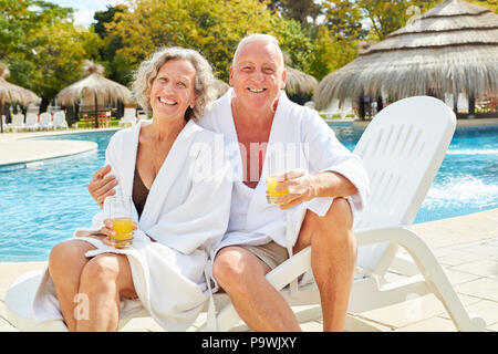 Happy senior couple in spa vacation by the pool with orange juice Stock Photo