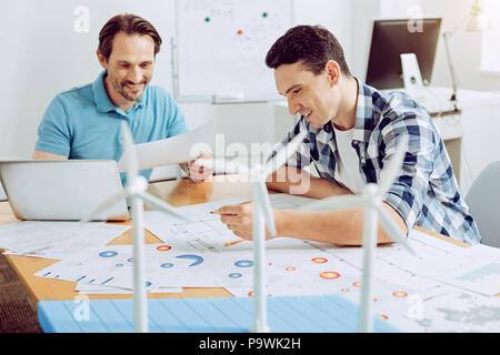 Smiling engineers. Positive skilled young engineers having a productive day while working at their common project Stock Photo