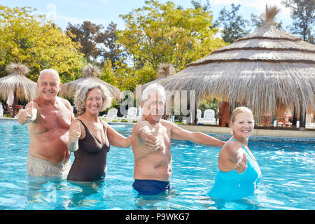 Cheerful group of seniors has fun in the pool and keeps their fingers crossed Stock Photo