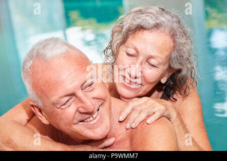 Amorous happy senior couple in swimming pool at wellness hotel Stock Photo