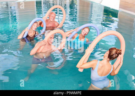 Group of seniors in aqua gym class is doing rehab exercises in swimming pool Stock Photo