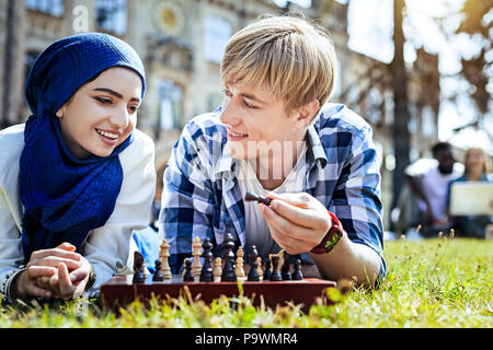 Friendly guy teaching girl playing chess Stock Photo