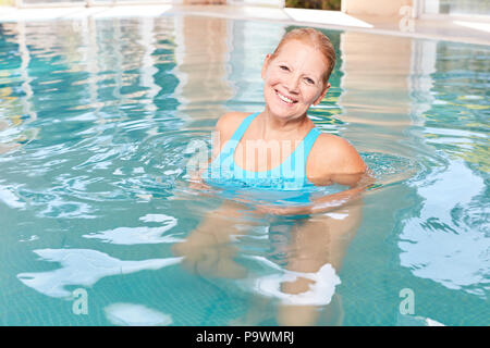 Smiling senior woman in the pool makes hydrotherapy for fitness and health Stock Photo