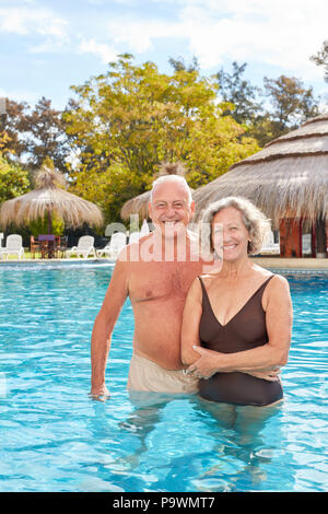 Happy senior couple is standing in the pool during a spa vacation at the luxury hotel Stock Photo