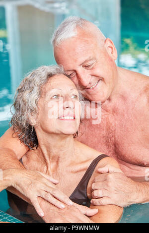 Amorous senior couple hugging each other in the swimming pool at the Wellness Hotel Stock Photo