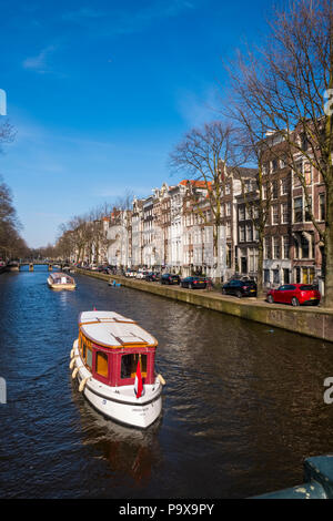Canal cruises in a pleasure boat with canal houses and tourist cruise boats on a canal in Amsterdam, The Netherlands, Europe Stock Photo