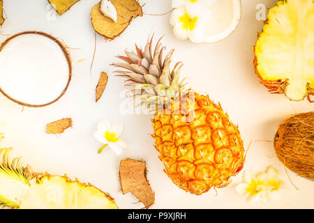 Summer flat lay scene with tropical fruits pineapples and coconuts on light gray wooden background, retro toned Stock Photo