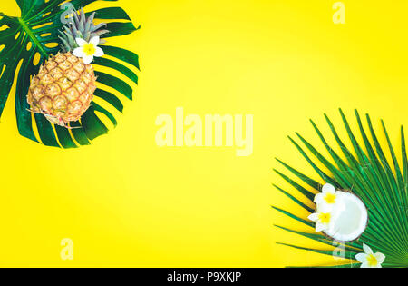 Summer flat lay frame with tropical green leaves, coco and pineapples frame on yellow, retro toned Stock Photo