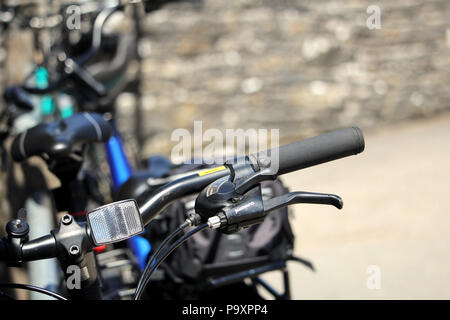 Corfe, Dorset, England - June 03 2018: Shallow focus close up of a bicycle handlbars showing reflector, brake lever, gear selector and other details,  Stock Photo
