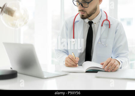 Doctor using laptop and electronic medical record (EMR) system. Digital database of patient's health care and personal information on computer screen. Stock Photo