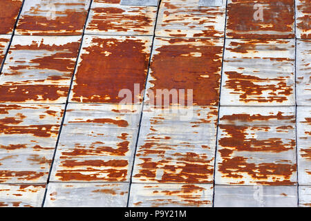 joined together metal sheet, from which the roof of the building is made, part of the metal surface is oxidized and rusted, closeup Stock Photo