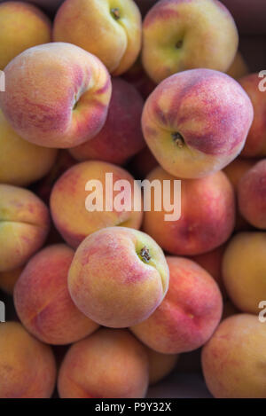 Ripe peaches stacked in a box at a local farm market Stock Photo