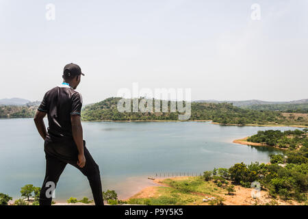A sport man standing on top of a mountain and looking ahead at the river and island Stock Photo