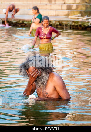 Indian sadhu man and 2 women bathing in the Ganges at dawn  Varanassi Indian Stock Photo