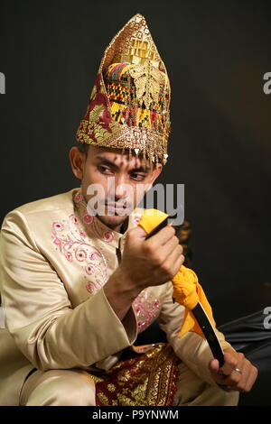 Handsome man in traditional acehnese dress holding Rencong (Traditional aceh weapon) Stock Photo