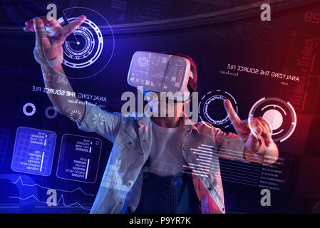 Smart girl touching round icons on the screen while using virtual reality glasses Stock Photo