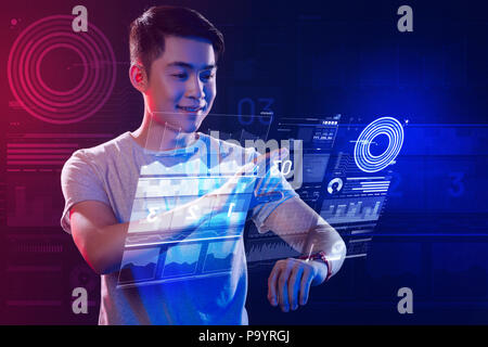 Positive web developer using a smartphone while working with holograms Stock Photo