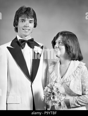 1970s TEEN COUPLE DRESSED UP FOR PROM DANCE FORMAL ATTIRE GIRL HOLDING BOUQUET LOOKING UP AT TALL BOY - j13789 HAR001 HARS JOY LIFESTYLE CELEBRATION FRIENDSHIP HALF-LENGTH INSPIRATION TEENAGE GIRL TEENAGE BOY CONFIDENCE EXPRESSIONS B&W EYE CONTACT DREAMS HAPPINESS CHEERFUL EXCITEMENT AT HIGH SCHOOL SMILES HIGH SCHOOLS CONNECTION JOYFUL STYLISH ATTIRE DRESSED UP GROWTH LOOKING UP TOGETHERNESS BLACK AND WHITE CAUCASIAN ETHNICITY HAR001 OLD FASHIONED Stock Photo
