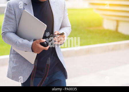Young stylish businessman leader checking photo DSLR outdoors walking to office. Stock Photo