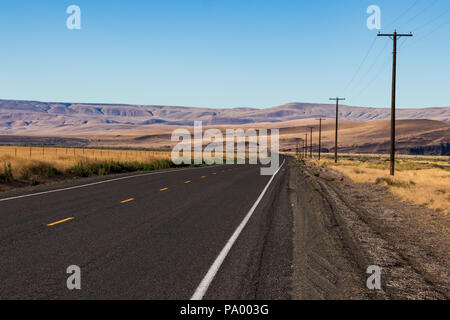 Palouse country highway going in to the distance in to rolling desert hills with a blue sky Stock Photo