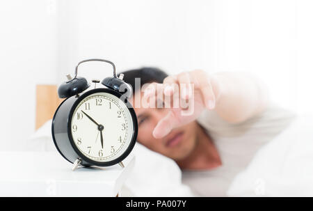 Man's hand is reaching out to alarm clock waking up in early morning Stock Photo