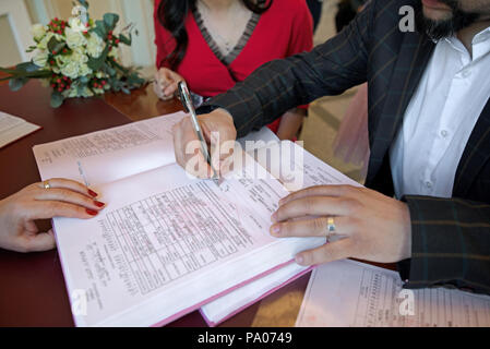 Beautiful ceremony. Wedding couple leaving their signatures. Concept of love and building the future together. The happiest day of their life. Stock Photo