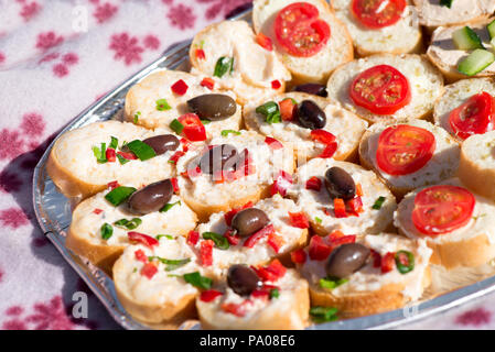 Variety of mini sandwiches with cheese cream, vegetables - roasted cherry tomatoes, olives, cucumber, spring onions, paprika, basil and other herbs. F Stock Photo