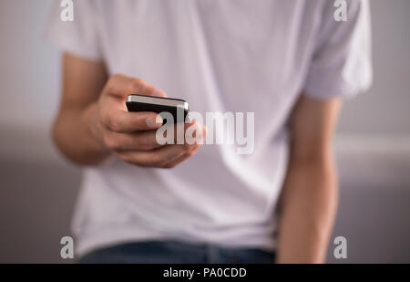 Young man using a touchscreen smartphone - Hands close-up - Using technology Stock Photo