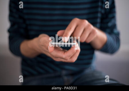 Young man using a touchscreen smartphone - Hands close-up - Using technology Stock Photo