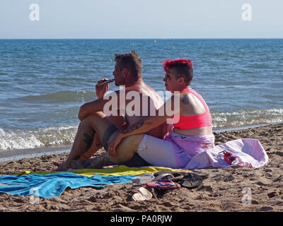 two people sitting close up and taking time out to enjoy their summer together at the beach in Sérignan Plage, South of France Stock Photo