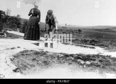 702 Genre painting, woman, man, puddle, bridge, field, hat, hillside, sunshades Fortepan 3539 Stock Photo