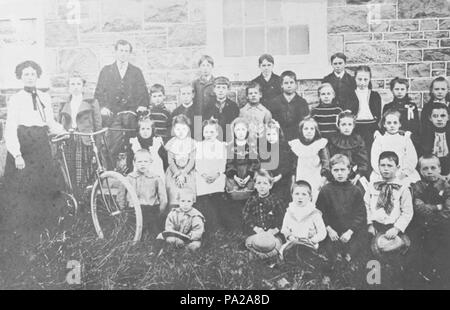 . English: A black and white school photograph from Whitby, Ontario, Canada. The Ashburn School was located at 780 Myrtle Road West. It was built about 1861 on the north side of the 9th Concession of Whitby Township west of Ashburn Road. It was built by a stone mason named Pearson. Since 1967 this building has been used as a community centre. In the photograph, there is a bicycle between Elizabeth Wilson and Laura Holman. The teacher of this class is Mr. McCullough. From left to right and back to front: Back Row: Elizabeth Wilson, Laura Holman, Mr. McCullough (teacher), Albert Cook, George Dav Stock Photo