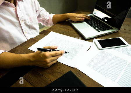 Businessman working at office with laptop and documents on the table, Businessman holding pens and papers taking notes in documents on the table. Stock Photo