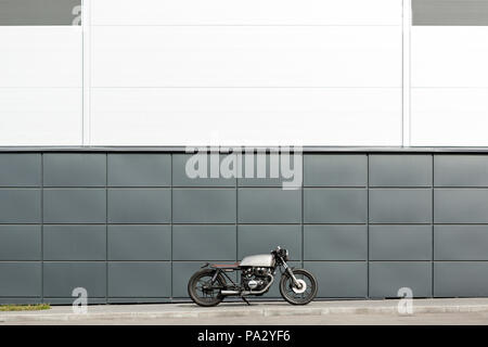 Custom motorbike parking near gray wall of finance building. Everything is ready for having fun driving the empty road on a motorcycle tour journey. C Stock Photo