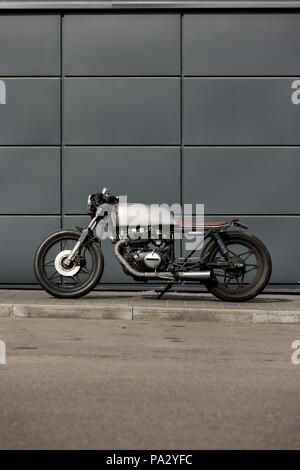 Custom motorbike parking near gray wall of industrial building. Everything is ready for having fun driving the empty road on a motorcycle tour journey Stock Photo