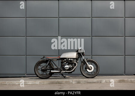 Custom motorbike parking near gray wall of finance building. Everything is ready for having fun driving the empty road on a motorcycle tour journey. B Stock Photo