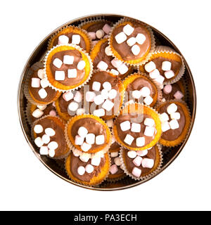 Cake tin full of homemade cup cakes with chocolate and marshmallows on a white background Stock Photo