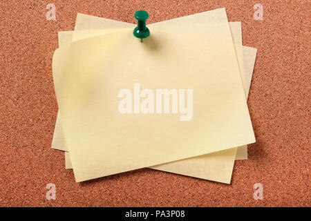 Several untidy yellow sticky post notes pinned to cork board Stock Photo
