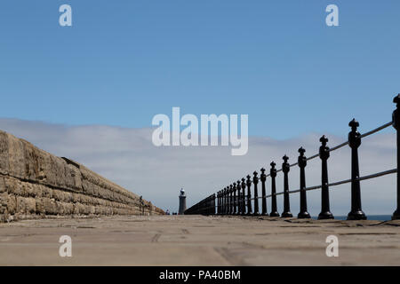 The North Pier at Tynemouth in England. A  lighthouse stands on the North Pier that was designed by John Wolfe-Barry and reconstructed in 1909. Stock Photo
